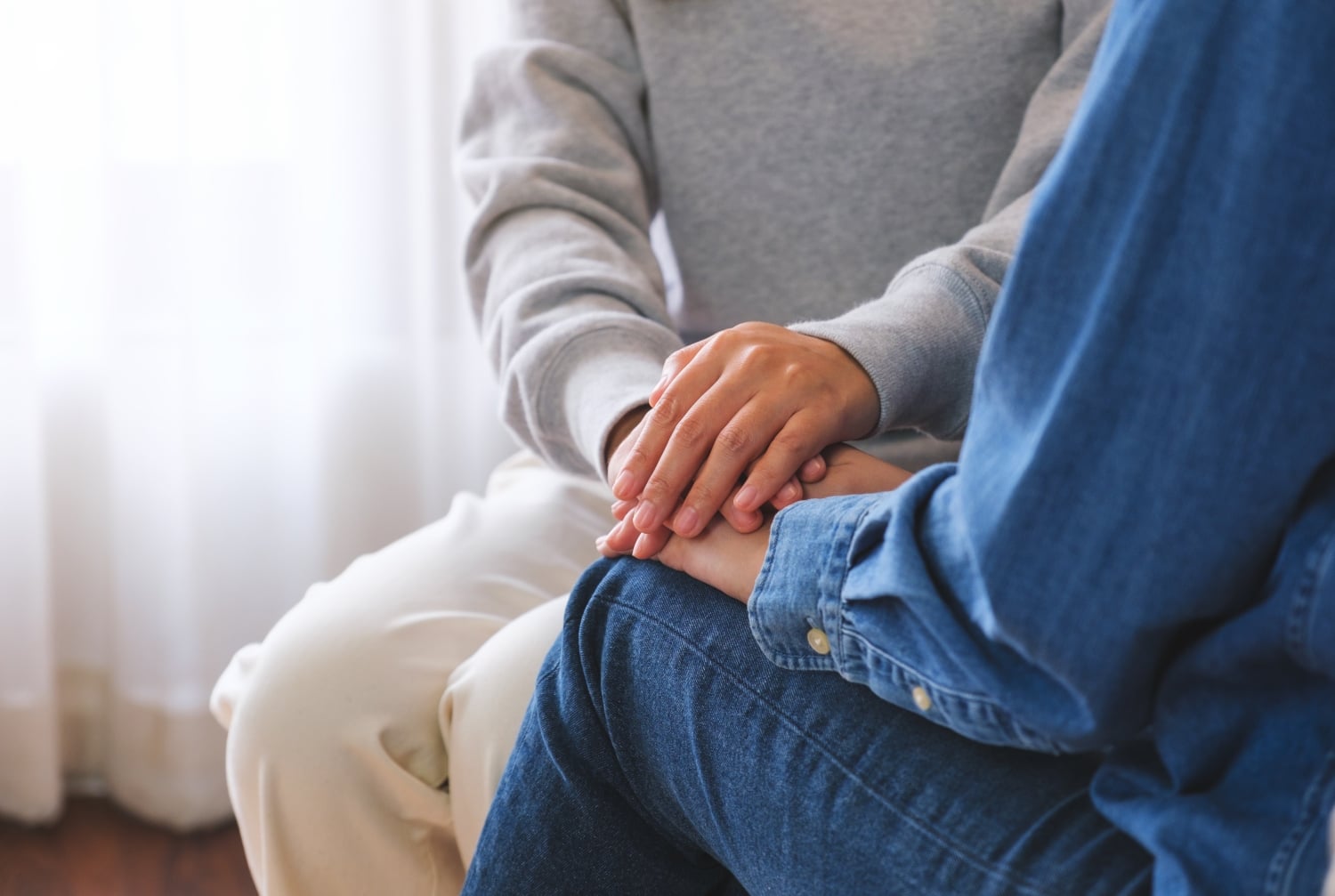 Supportive Embrace Holding Hands Indoors Near Window, Concept of Helping