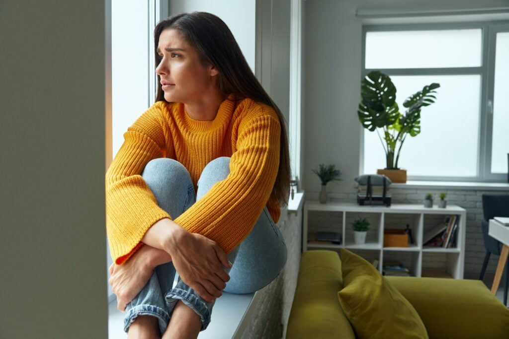 Woman Sitting by Window in Thoughtful Mood