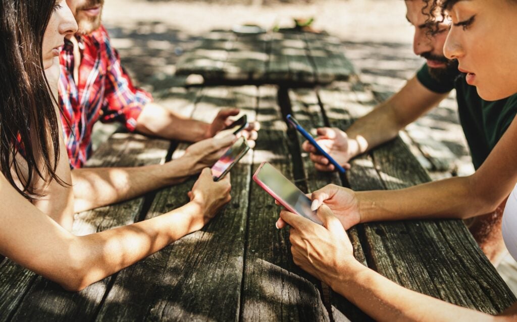teenagers using smartphone sitting outdoors