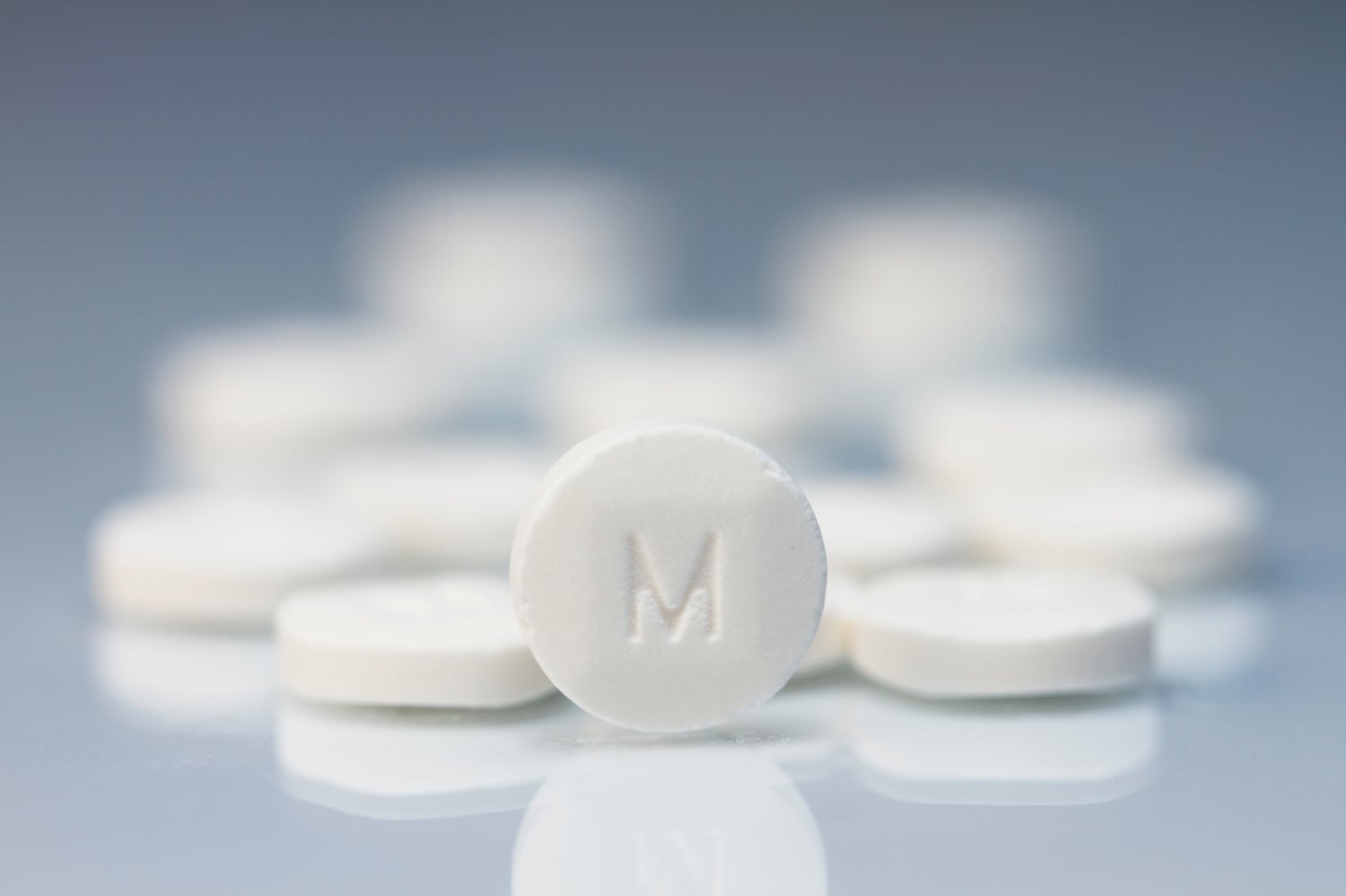 white pill with letter M, concept of addiction